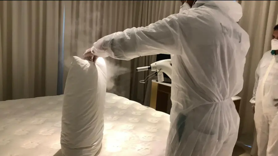 An iPurity technician fogging a pillow, the disinfectant mist visible in the air